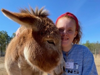 A girl poses with a donkey.