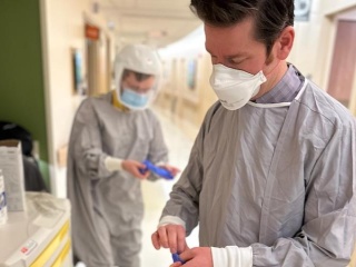 Gowned and masked providers putting on gloves at UVM Medical Center. 