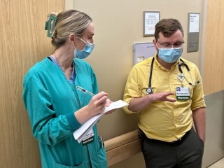 Two masked providers in discussion in clinic