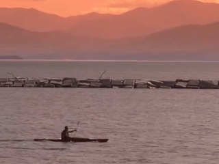 Kayaker on Lake Champlaign with sunset over mountains in background