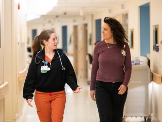 Two nursing talking as they walk down hospital hallway
