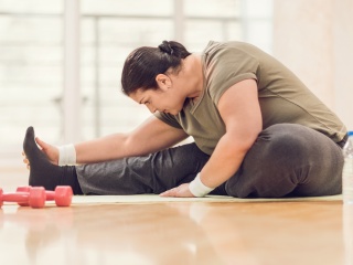 A woman stretches next to weights.