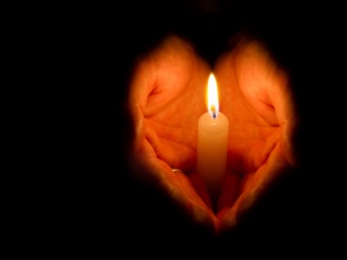 Close-up of a hand holding a lit candle.