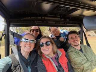 Five OBGYN residents smile for group photo in an off road vehicle.
