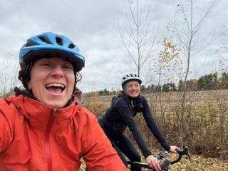 OBGYN resident smiles for a selfie while riding bikes with a fellow resident and bike rider.