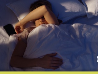 A man lying awake in bed with his arm over his face