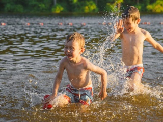 Two young boys play in the lake.