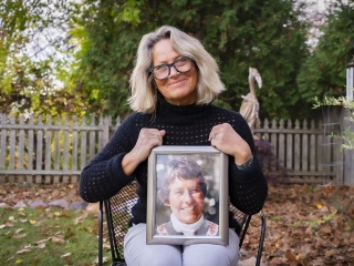 Erica Lustgarten sits outside holding a portrait of her mom, Albertine DeGroot.