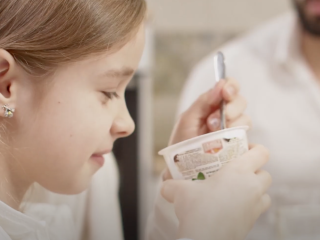 Young girl eating yogurt. 