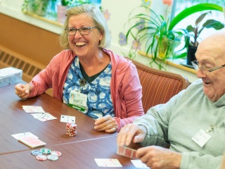 A Home Health and Hospice nurse plays poker with an adult male patient.
