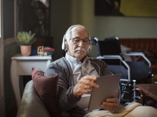 A senior man uses a tablet at home.