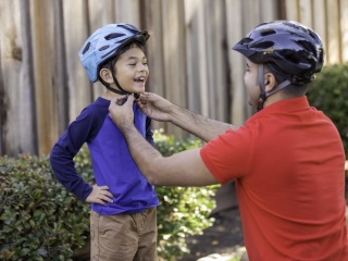 A father attaches bike helmet for sports safety. 