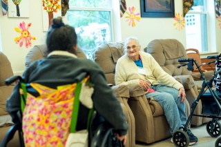 Home Health & Hospice Adult Day Program participants chat in a common room.