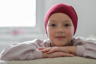 Photo of smiling child wearing a head scarf in the hospital.