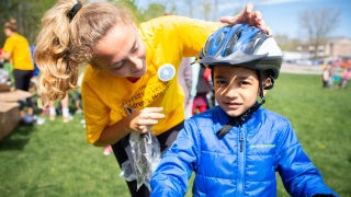 A woman secures a helmet on a child's head.