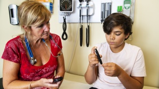 A medical provider assists a child with checking their insulin levels. 