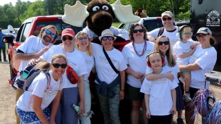 Patient and family advisors pose with Monty the moose at a memorial day parade.