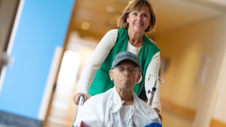 A volunteer pushes a patient in a wheelchair.