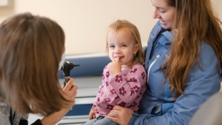 A child smiles while examined by a provider at Porter Medical Center Pediatrics.