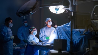 Surgeons look on to a screen during a surgery.