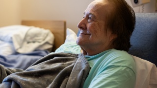 A resident smiles while sitting in a chair.