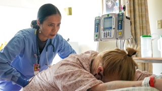 A medical provider pushes on the lower back of a patient in labor.
