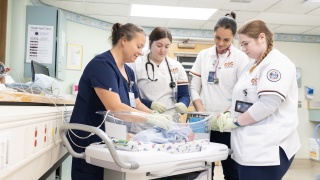 Champlain Valley Physicians Hospital labor and delivery nurse works with Clinton Community College students on taking care of a newborn baby.