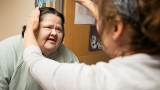 A Champlain Valley Physicians Hospital Skilled Nursing Facility resident has her hair brushed by a staff member.