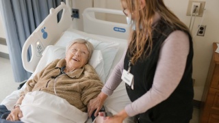 A Porter Medical Center Nurse comforts a patient in a hospital bed.
