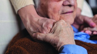 Senior adult male holds hands with caregiver