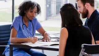 Provider reviews documents, sitting across the table from husband and wife.