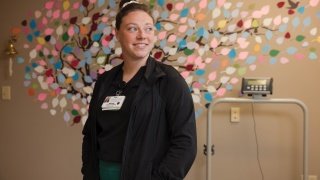 An Alice Hyde Medical Center nurse stands in front of a mural at the Reddy Cancer Treatment Center.