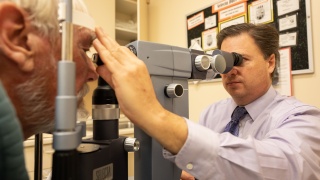 An adult patient receives an eye exam from an ophthalmologist at UVM Medical Center.