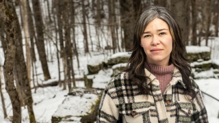Casey Kolb Nava stands in the snowy woods in the winter.