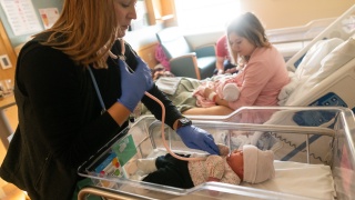 A provider listens to the heart of a newborn baby, while the mother holds it's twin at University of Vemont Medical Center.