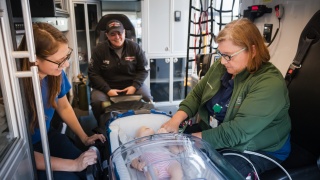 Paramedics sit in an ambulance and train on a baby dummy.