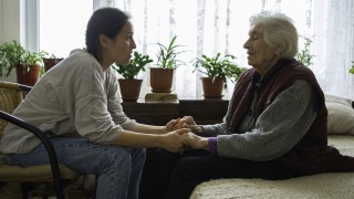 Volunteer woman caretaker talking with senior woman.