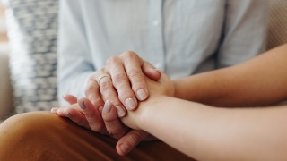 Up close photo of senior woman holding hands with a child. 