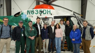 Stahl Family and UVM Health Network staff pose in front of hospital helicopter.