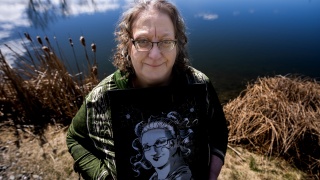 StaciAnn Grove stands with artwork by a pond.