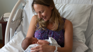 A patient holds their newborn baby in bed.