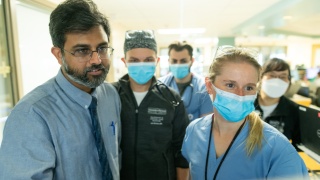 A medical provider and medical students look at a computer screen.