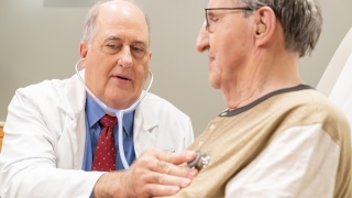 David Schneider, MD, of UVM Medical Center, examines an adult patient with a stethescope.