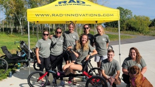 A team of participants poses in front of a tent.