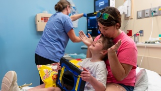Mother and child play in a hospital bed awaiting a medical procedure.