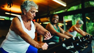 Adult woman riding stationary exercise bike at fitness center.