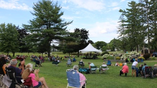 People sit in lawn chairs watching a concert.