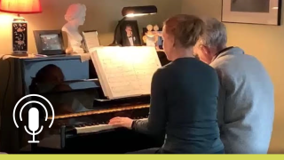 Two people play on a piano.