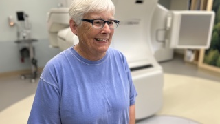 Maggie Frampton poses for a photo next to LINAC radiation therapy.