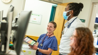Three physicians smile and stand together.